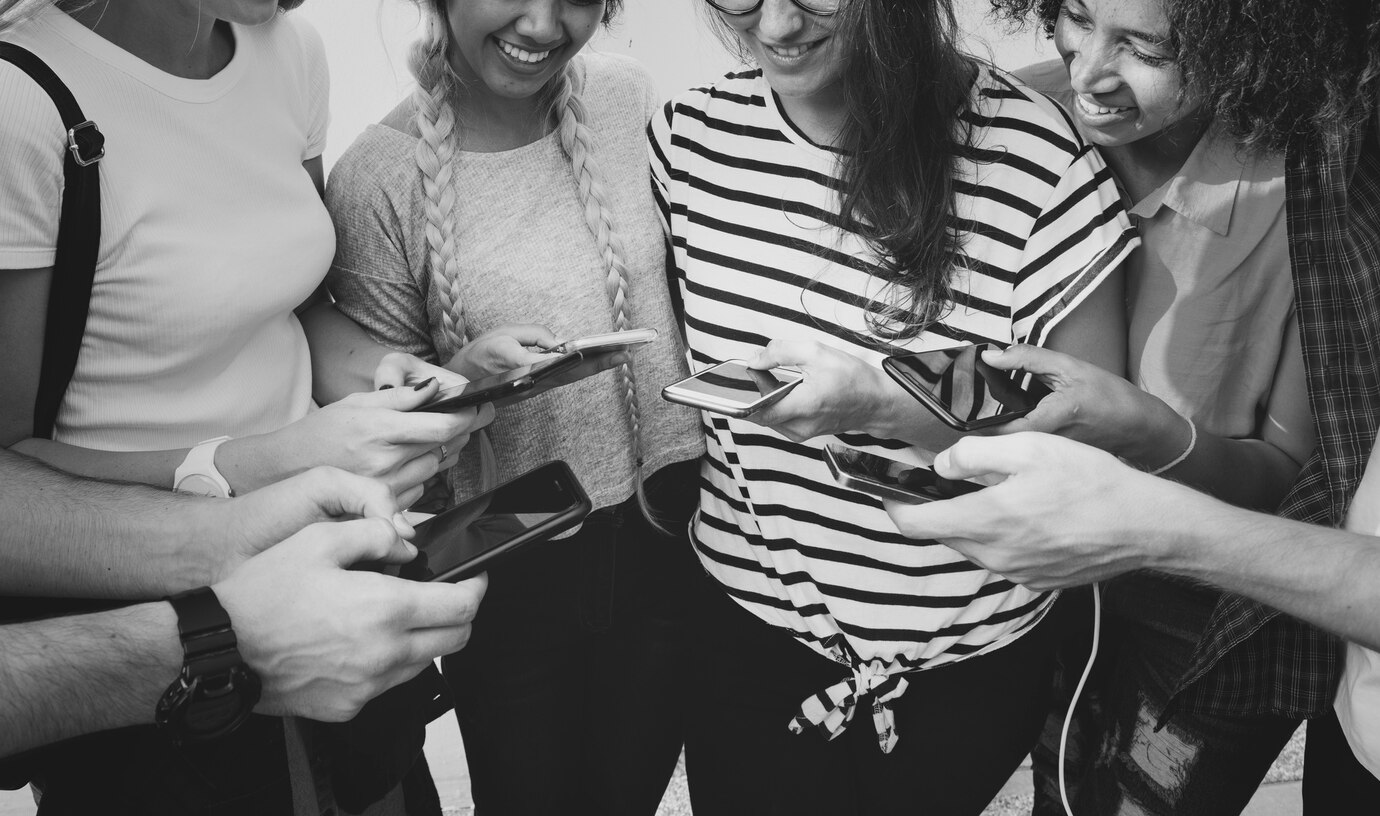Young adult friends using smartphones together