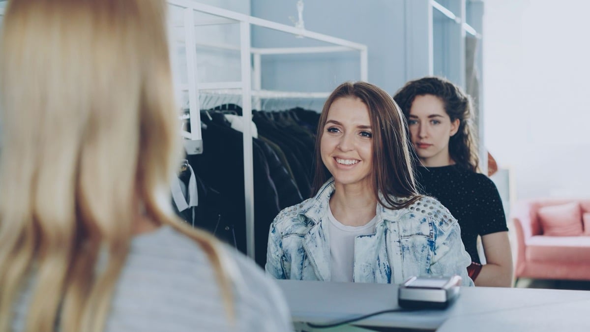 A repeat customer chatting with staff at a clothing store checkout